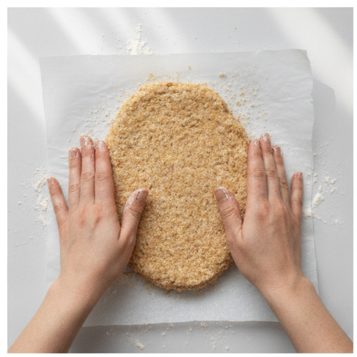 Shaping ground chicken into a thin oval on floured parchment paper