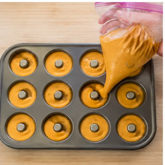 Piping the batter into greased mini donut wells with a zip-top bag