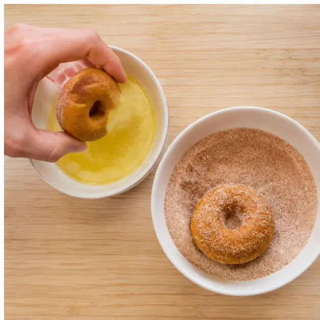 Dipping baked donuts in melted butter and coating with cinnamon sugar
