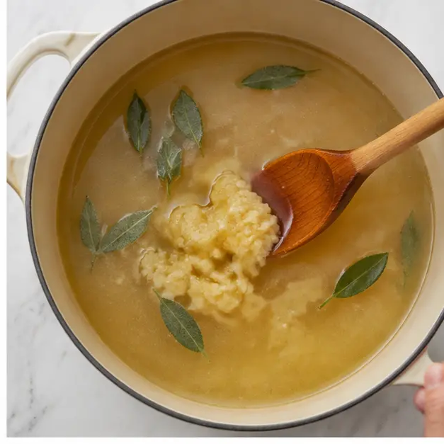 Step 2: Mash the garlic and stir it into simmering chicken stock with sage