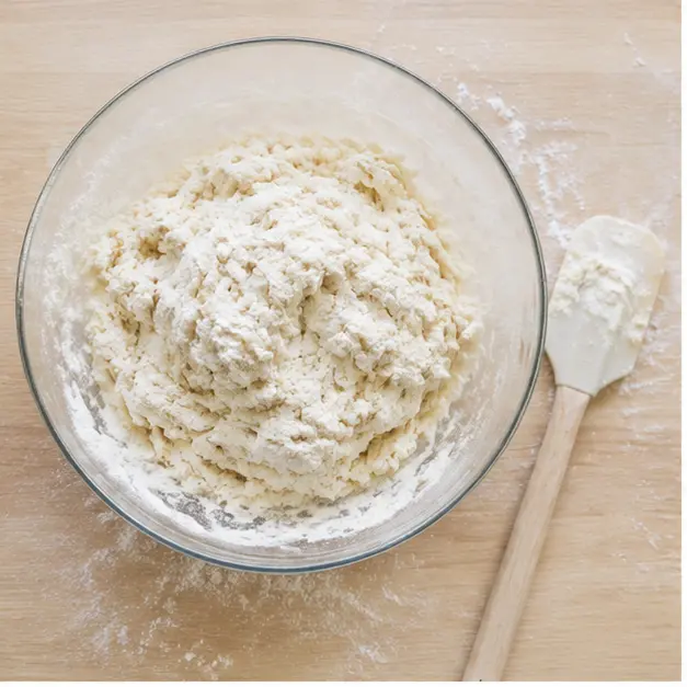 Mixing flour, baking powder, salt, and Greek yogurt into a shaggy dough