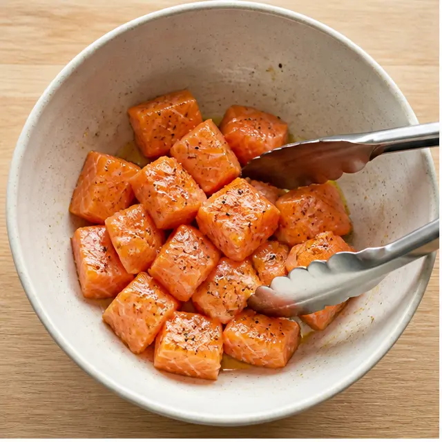 Step 1: Tossing raw salmon cubes with olive oil and seasonings