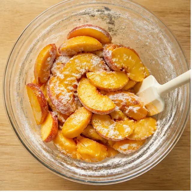 Step 1: Slicing ripe peaches and tossing them with flour, sugar, lemon juice, and vanilla until evenly coated, glistening fruit in a large bowl