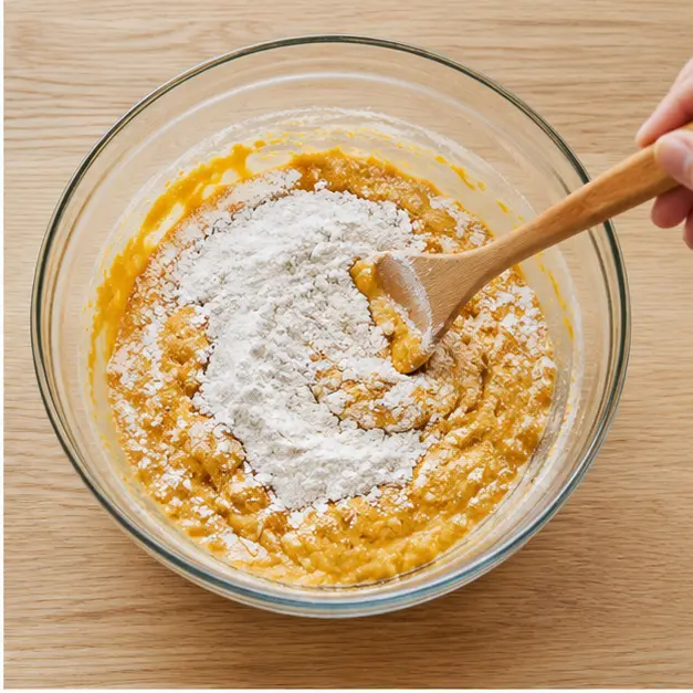 Adding flour and baking powder, stirring until just combined