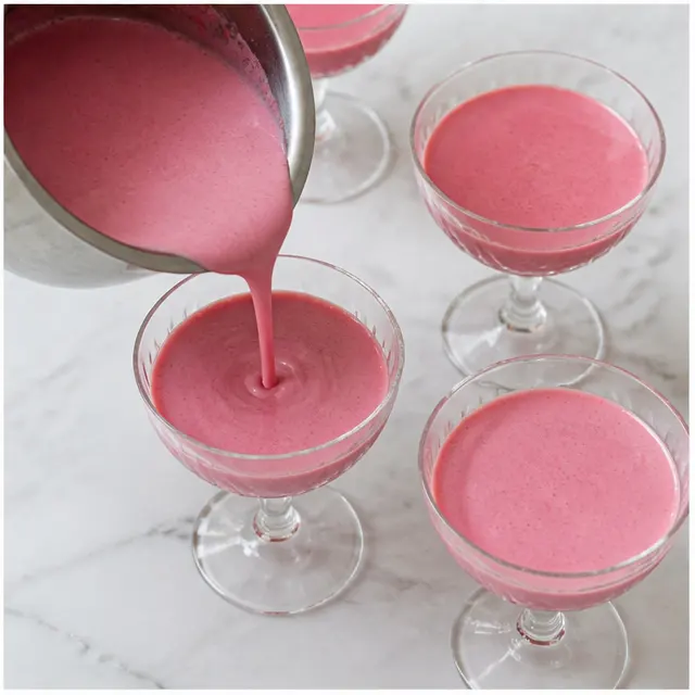 Pouring the smooth posset into clear glass serving coupes to chill