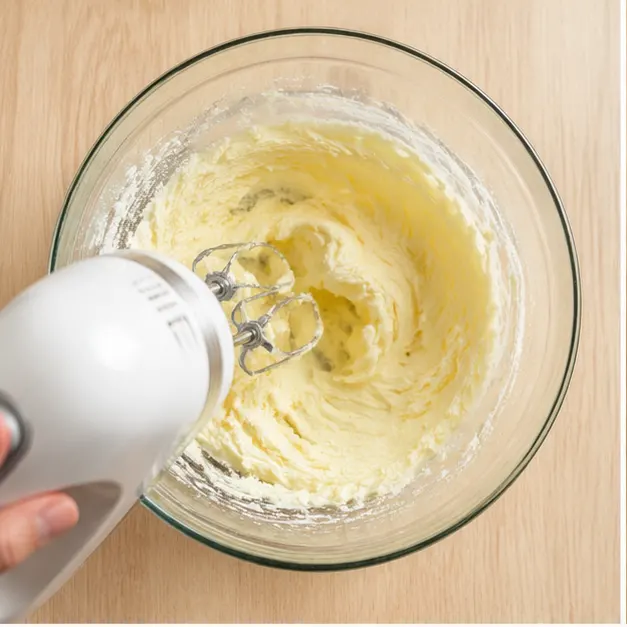 Cream softened butter and granulated sugar into a thick glossy paste, then mix in the egg, eggnog, and rum extract