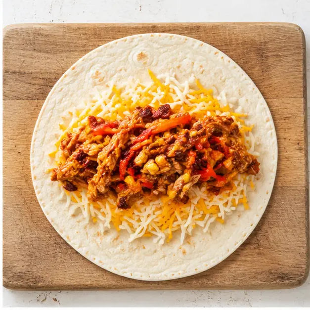 Step 2: Build each quesadilla on a cutting board, shredded cheddar and Monterey Jack first, then chipotle-honey chicken, corn and pepper strips, then more cheese and a second tortilla