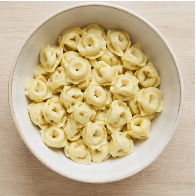 Step 3: transfer cooled drained cheese tortellini pasta into a wide cream ceramic mixing bowl